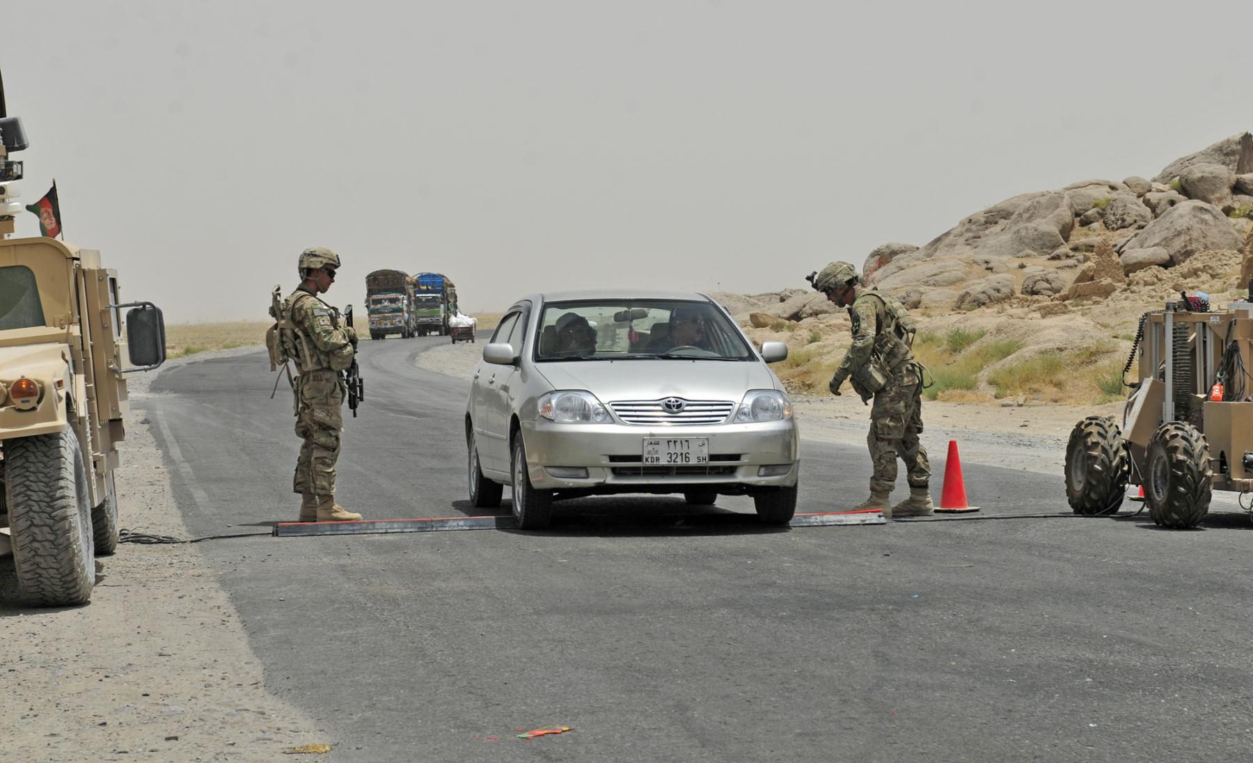 U.S. Soldiers conduct traffic control operations at a checkpoint.