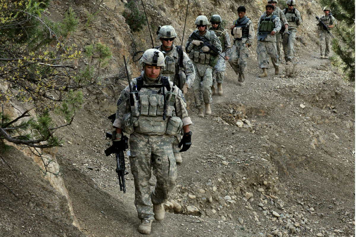 Soldiers and Afghan Border Police walk along a mountain trail during a patrol