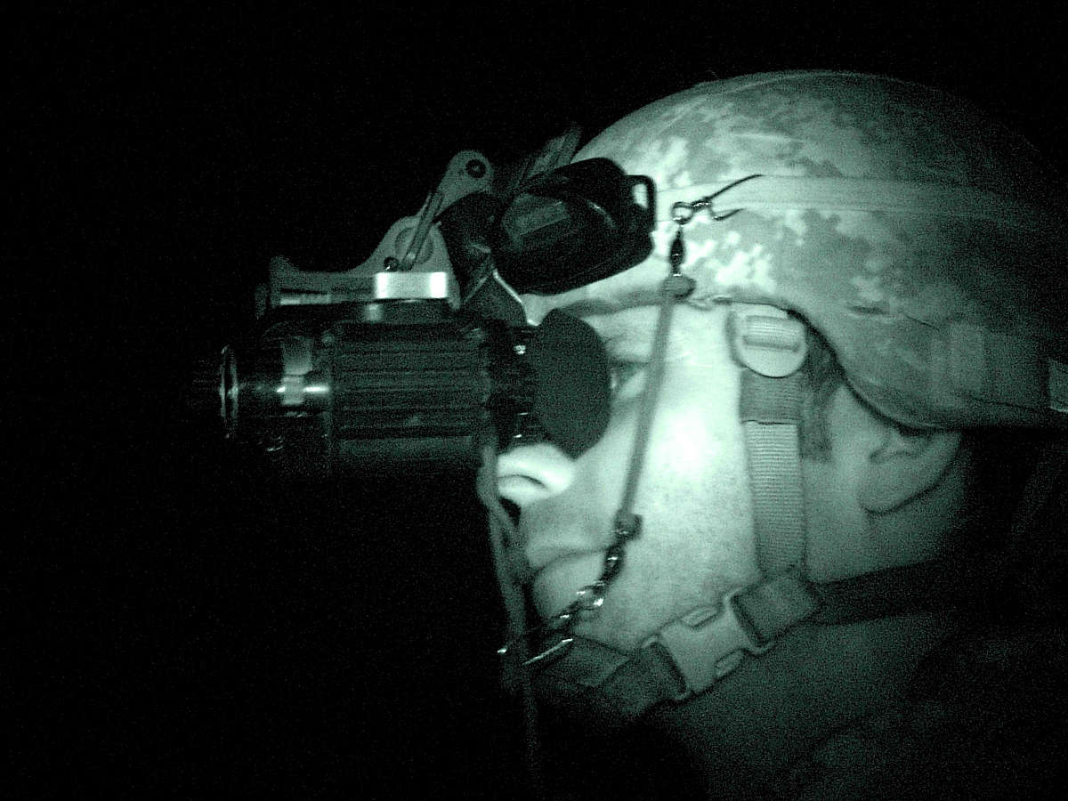 A Soldier uses his night vision goggles while on night patrol.