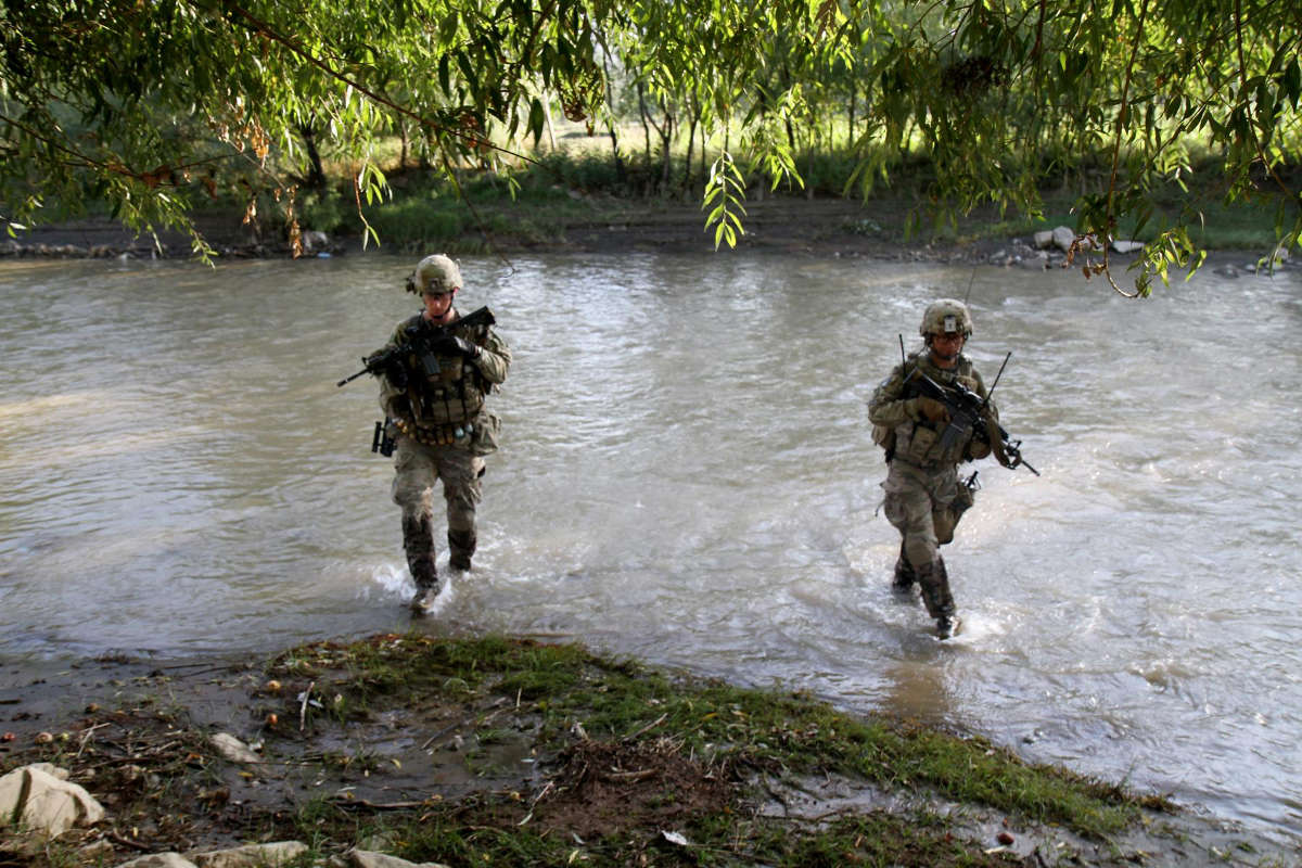 Soldiers cross a small stream while on a foot patrol